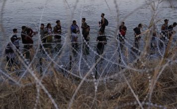 FILE - Migrants wait to climb over concertina wire after they crossed the Rio Grande and entered the U.S. from Mexico, Sept. 23, 2023, in Eagle Pass, Texas. (AP Photo/Eric Gay, File)