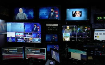 FILE - TV anchor Nesar Nabil is seen on studio monitors wearing a face mask to protest the Taliban's new order that female presenters cover their faces, as he reads the news on TOLOnews, in Kabul, Afghanistan, Sunday, May 22, 2022. (AP Photo/Ebrahim Noroozi, File)