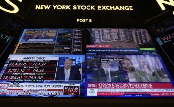 Financial news is displayed as people work on the floor at the New York Stock Exchange in New York, Tuesday, March 4, 2025. (AP Photo/Seth Wenig)