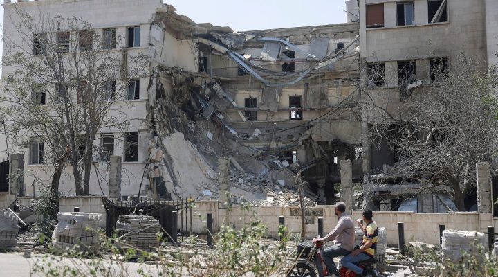 People pass in front the Syrian Defense Ministry building which was heavily damaged by Israeli airstrikes in Damascus, Syria, Thursday, July 17, 2025. (AP/Ghaith Alsayed)