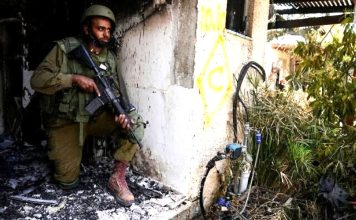An Israeli soldier takes a position in Kibbutz Kfar Azza on Tuesday, Oct. 10, 2023. (AP Photo/Ohad Zwigenberg)