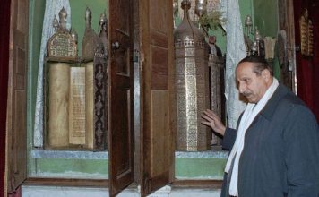 Illustrative. In this January 21, 2000, file photo, Youssef Jajati, a Jewish community leader in Syria, points at Torah scrolls preserved in a silver container in the Jobar Synagogue in Damascus. (AP Photo/ Bassem Tellawi, File)