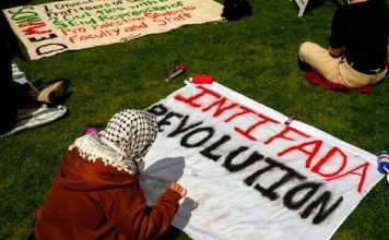 A person prepares a sign reading 'Intifada Revolution' at an anti-Israel encampment at the University of Washington campus, Monday, April 29, 2024, in Seattle. (AP Photo/Lindsey Wasson)